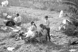 Una madre repasa la cabeza de su hijo mientras el hermano mayor repasa a su vez la cabeza de la madre buscando la presencia de parásitos, en 1970.