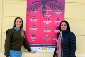 La edil y la alcaldesa junto al cartel de actividades por el 8 de marzo.