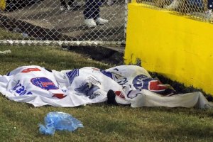 Una manta cubre varios cadáveres sobre el césped del Estadio Cuscatlán. / MILTON FLORES
