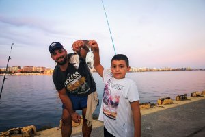 Un niño con su padre, en un concurso de pesca en el Puerto de Almería.