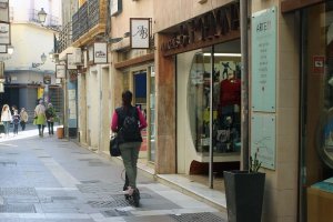 Una joven en patinete por una calle peatonal