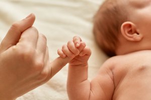 Una madre sostiene con su dedo a un bebé.