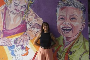 La artista Tati Salvador posa en uno de los murales que ha pintado en la fachada de su centro \'Tu Arte lo Parte\'.