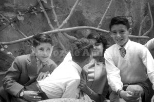 Un niño se acerca con descaro a los labios de una niña insinuando un beso. Año 1959. Chalet de Santa Rita.