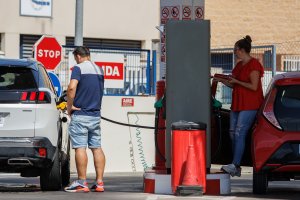 Dos personas echan gasolina a su vehículo en una estación de servicio.
