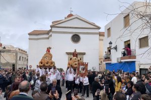 Los costaleros levantan los santos al cielo antes de comenzar la procesión de la lluvia de pan.