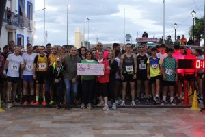 Autoridades, corredor y miembros de la AECC con el chuque de la donación.