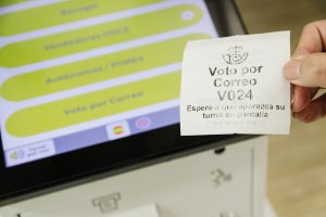 Una persona con un ticket de voto por correo en la oficina de Correos.