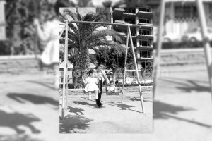 Una madre de los años setenta jugando con sus hijas en los columpios del Parque Nuevo.