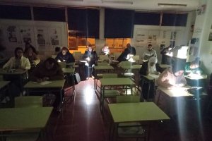 Alumnos realizando el examen con la linterna del móvil.