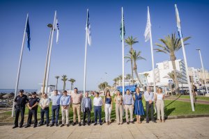 Las autoridades posan delante de las recién izadas banderas.