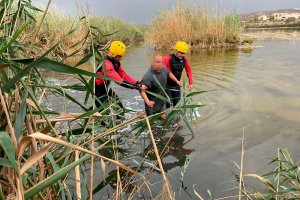 Binomio de bomberos ayudando al hombre caído en la Laguna de Vera.