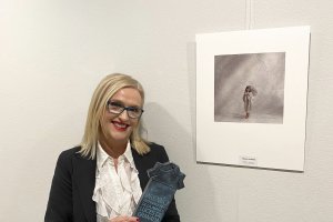 La fotógrafa junto a la imagen y con el galardón logrado.