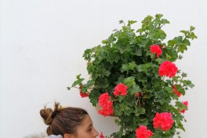 Una visitante disfruta del aroma de una de las macetas que cuelgan de una fachada de Lucainena de las Torres.