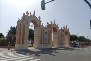 Un operario repinta la portada de la feria de la noche