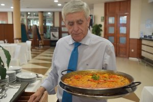 Eduardo Fernández portando una paella.