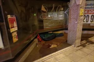 En la puerta del local duerme con su mochila roja.