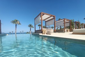 Una piscina increíble con las camas balinesas, hamacas y el Mediterráneo al fondo.
