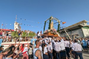 Los costaleros alzan a la virgen para embarcarla.