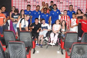 Jugadores y niños juntos en la sala de prensa del club.