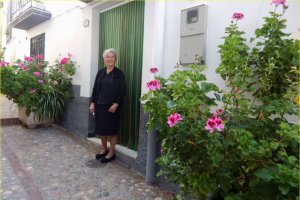 La señora Dolores de Alcolea, junto las flores a la puerta de su casa.