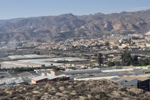 El primer plano las naves del polÍgono con la sierra al fondo.