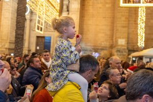 Una niña se toma los tomatitos cherry a hombros de su padre durante las 'Precampanadas'.