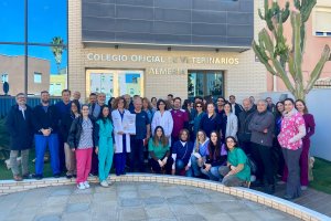 Decenas de veterinarios almerienses posan frente al Colegio Oficial de Veterinarios de Almería con un cartel de protesta en las manos.