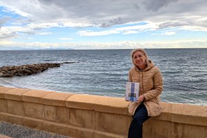 María José López Carmona posa junto al mar con su nuevo libro en las manos.