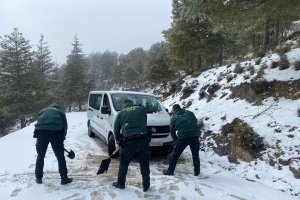 Agentes de la Guardia Civil limpian el asfalto con palas para poder liverar a los vehículos atascados.
