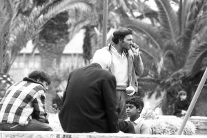 Un niño betunero limpiando zapatos en el Parque de los columpios en presencia del vendedor de las pelotas de plástico.
