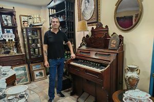 El anticuario Serafín Gutiérrez, de Antique, junto a un armonio (una especie de piano) de Boston de la época del viejo oeste americano.