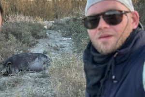 David, uno de los jóvenes que a veces se acerca a llevarle comida, y el popular porcino de fondo descansando entre matorral y basura en el cauce del Andarax.