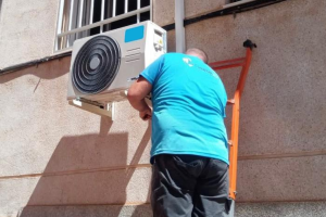 Un almeriense instala un aparato de aire acondicionado a las afueras de un edificio.