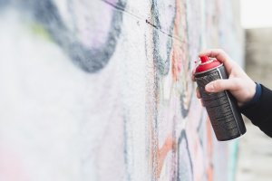 Una persona pintando una pared con aerosol.