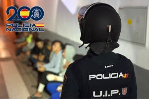 Detenidos durante el operativo son custodiados por un agente de Policía Nacional.