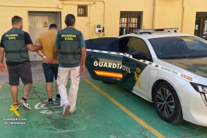 Dos guardias civiles escoltan al detenido hasta el coche oficial.
