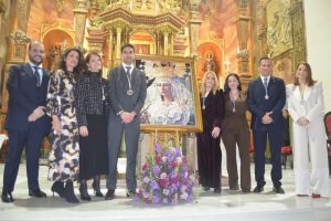 El Pregonero y la Hermana Mayor del Paso Blanco junto al equipo de gobierno posan junto al Cartel de Semana Santa 2026