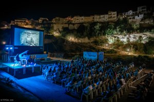 Vista general de la sesión de cine a cielo abierto con el aforo completo y un pianista interpretando en directo la banda sonora de la noche