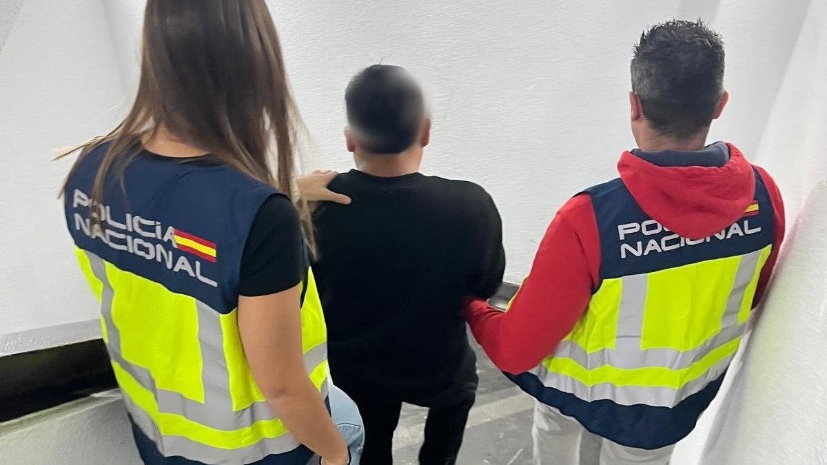 El detenido, de espaldas, custodiado por dos agentes de la Policía Nacional.