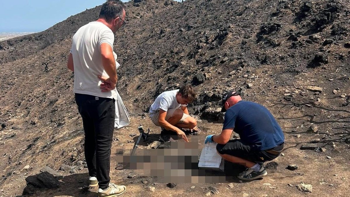 Un agente de la Guardia Civil, recogiendo restos óseos un mes y medio después del incendio en presencia del hijo de una de las víctimas y el alcalde de Bédar.