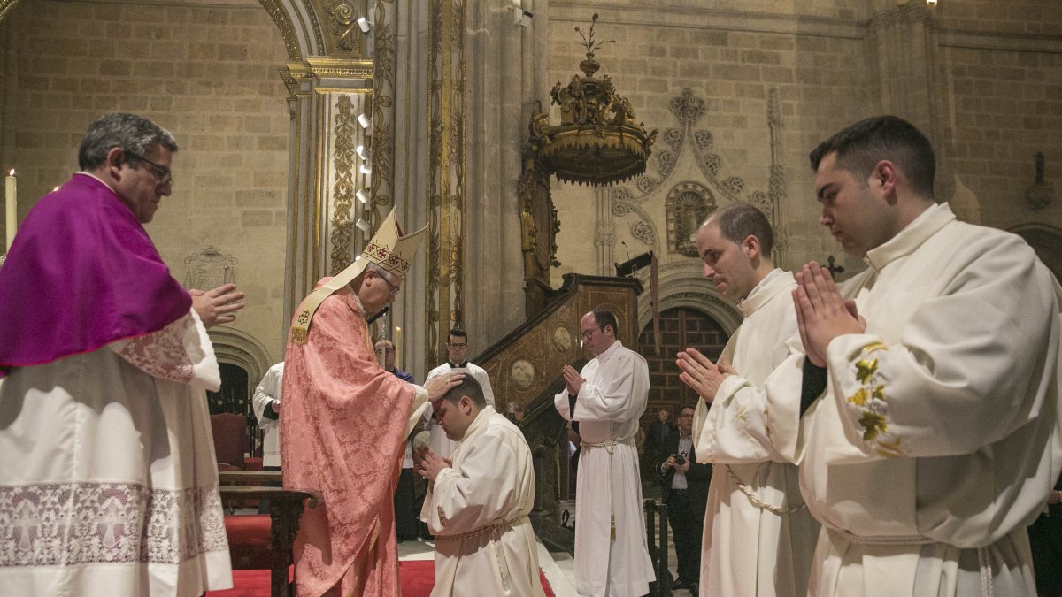 El obispo impone sus manos sobre los nuevos diáconos en la ceremonia.