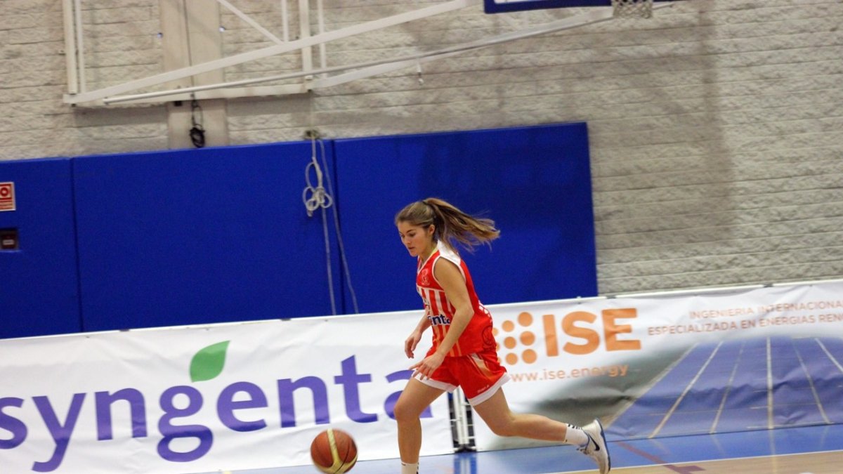 La jugadora rojilla camino de la canasta.