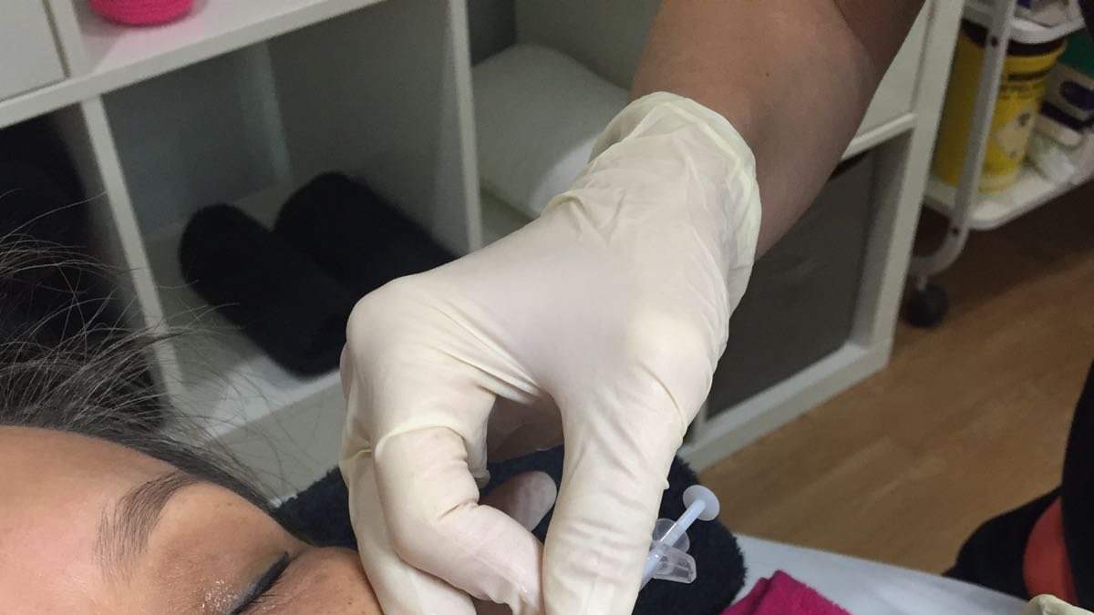 Una profesional  de FarmaEstetic aplicando bótox.