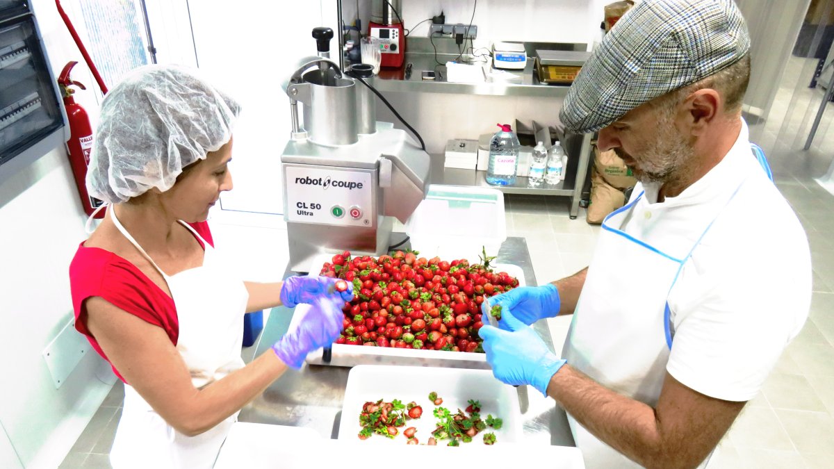 Isabel y biagio pelando fresas para mermelada en la fábrica que fue una carpintería.