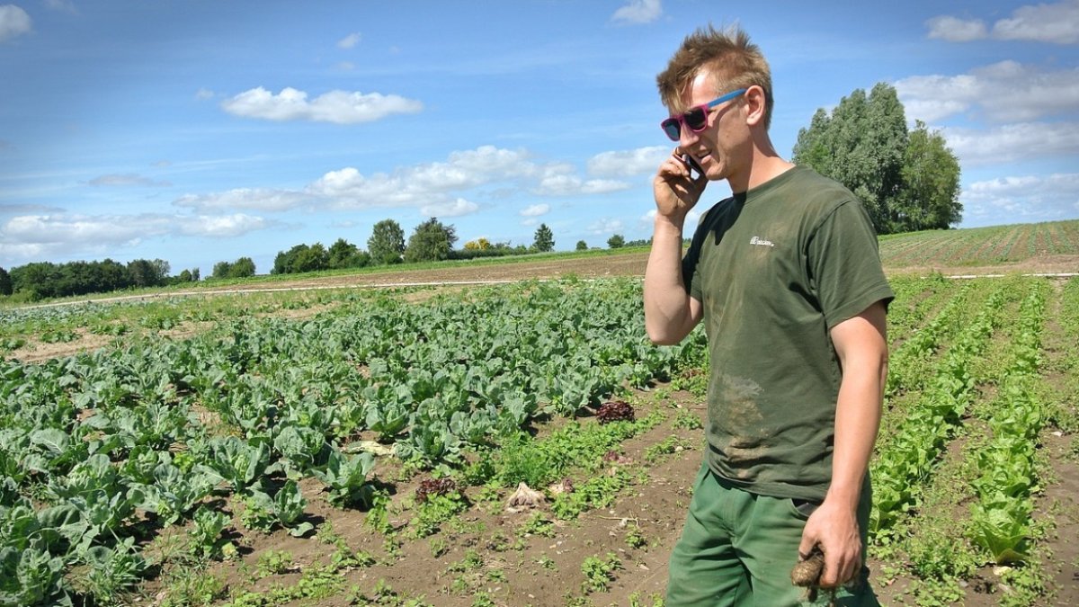 Un joven agricultor habla por su teléfono móvil.