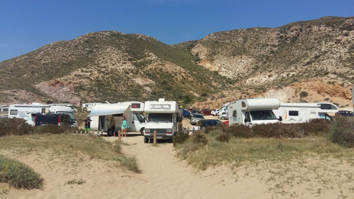Decenas de coches y autocaravanas en el Playazo de Rodalquilar, algunas de ellas con toldos y mobiliario sacados.