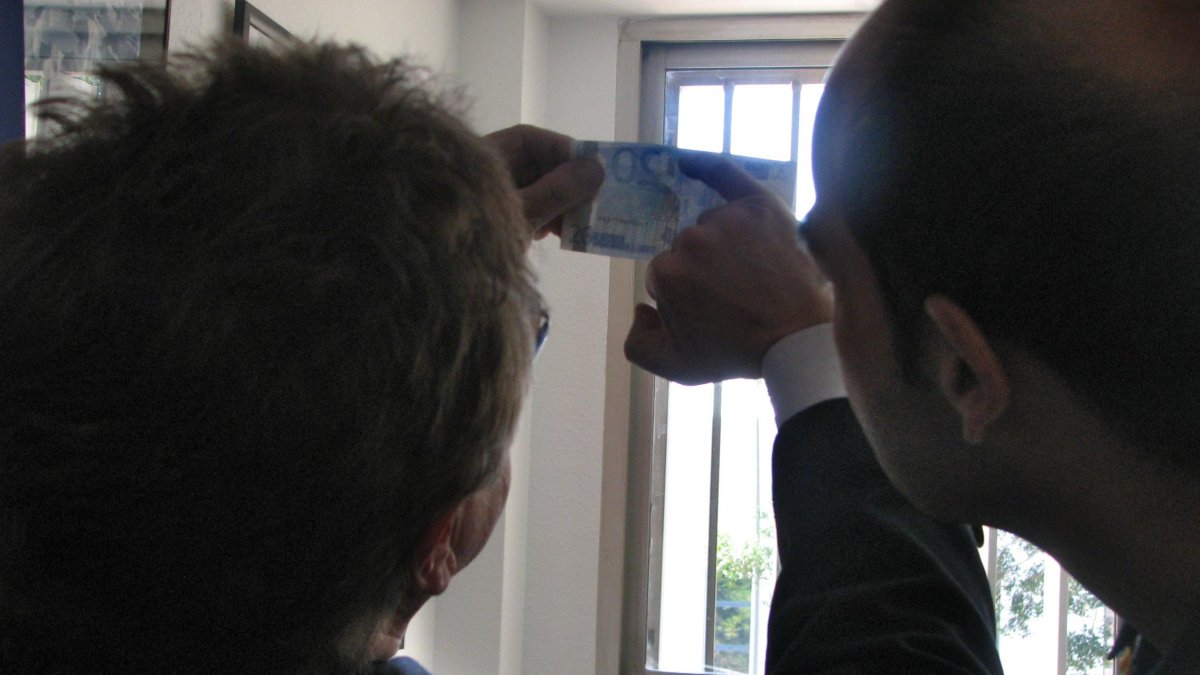 Un agente muestra los rasgos de seguridad de un billete