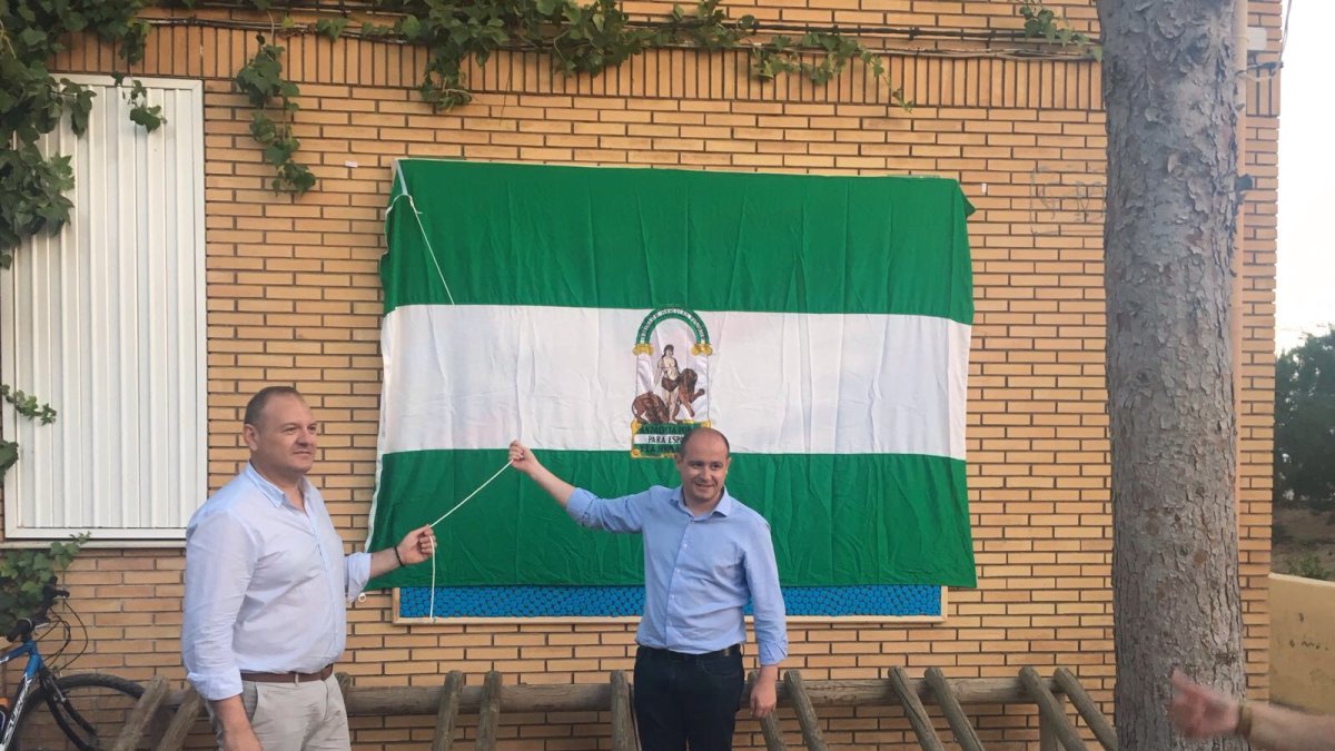 El delegado de Medioambiente y el alcalde izan la bandera.