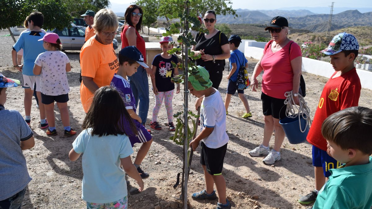 Los pequeños plantan uno de los árboles ante la atenta mirada de sus madres.